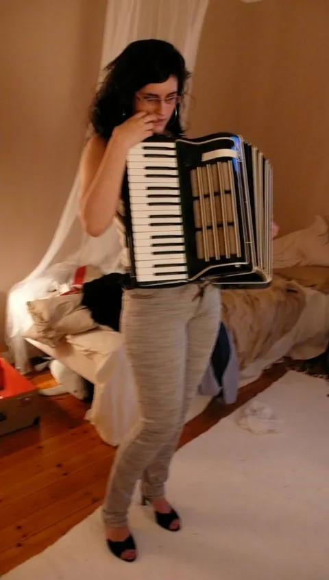 Woman playing an accordion in a warm-lit living room
